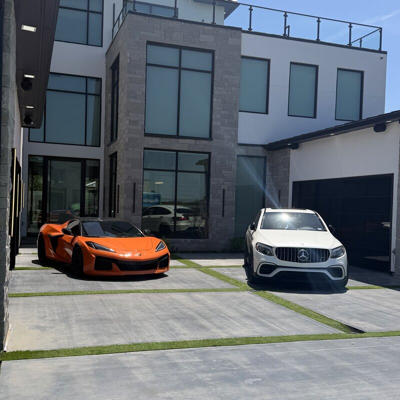 White Corvette Z06 and white Mercedes-AMG GLC 63 S parked in a modern driveway