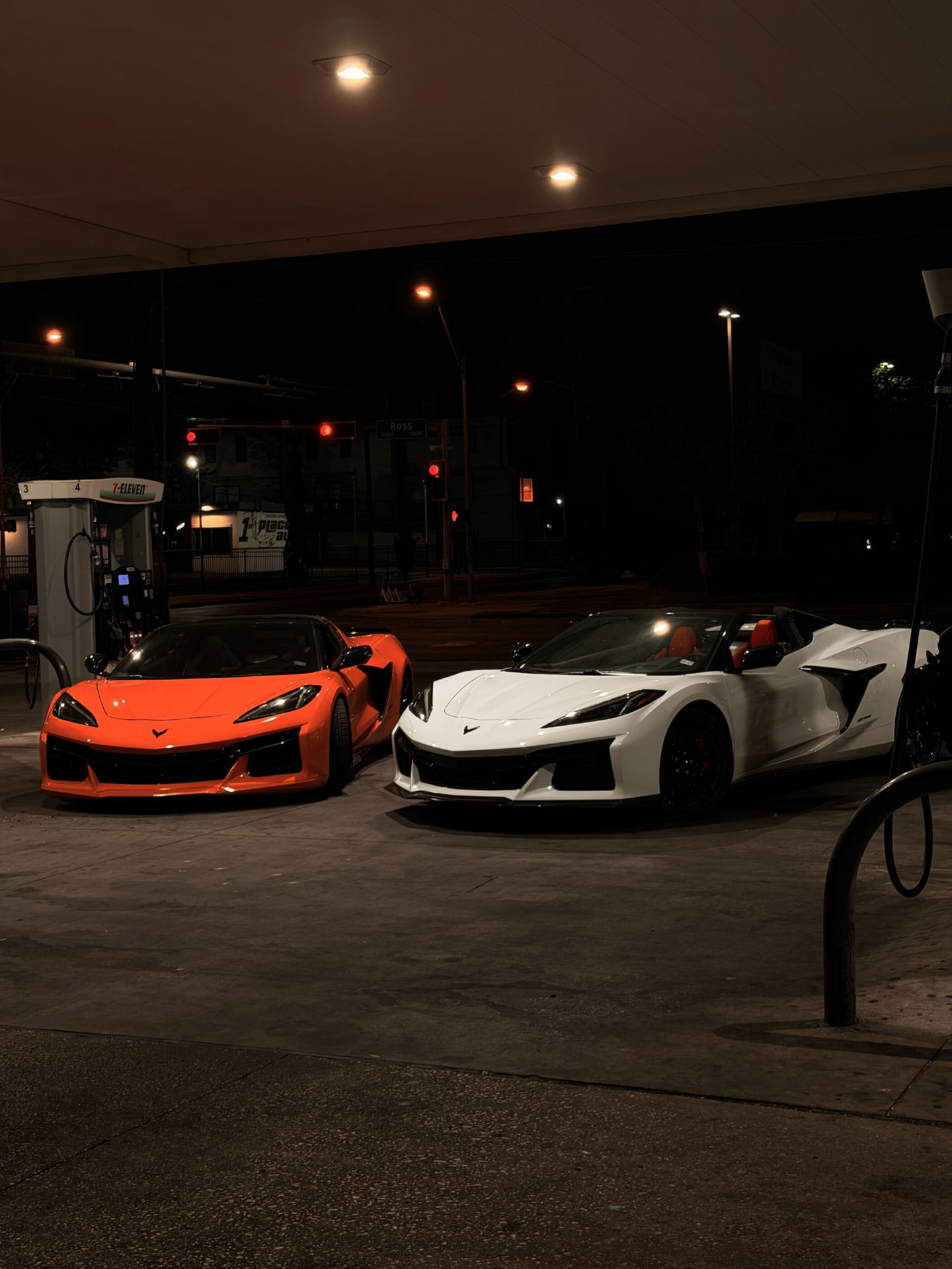 Two Corvette Z06 exotic car rentals at a Dallas gas station at night