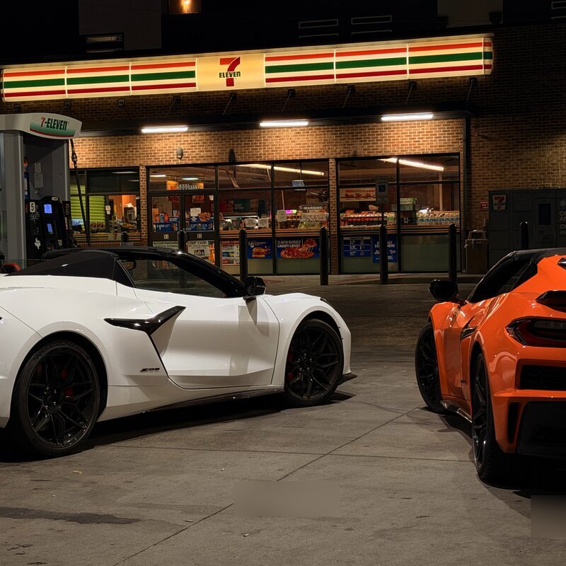 White and orange Corvette Z06 rentals at a Dallas gas station at night